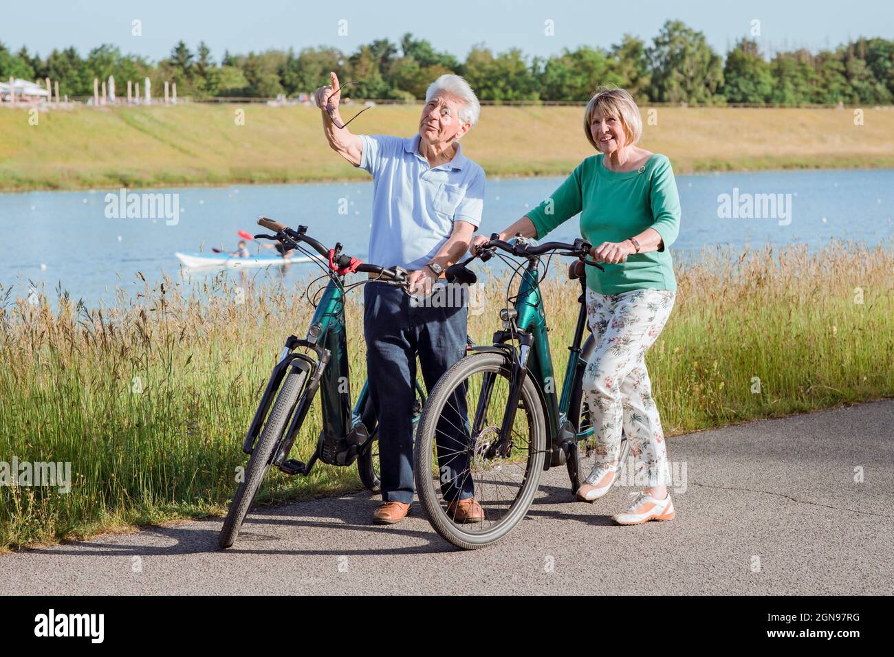 Uomo anziano che punta mentre parla con la donna in piedi dalle biciclette Foto Stock