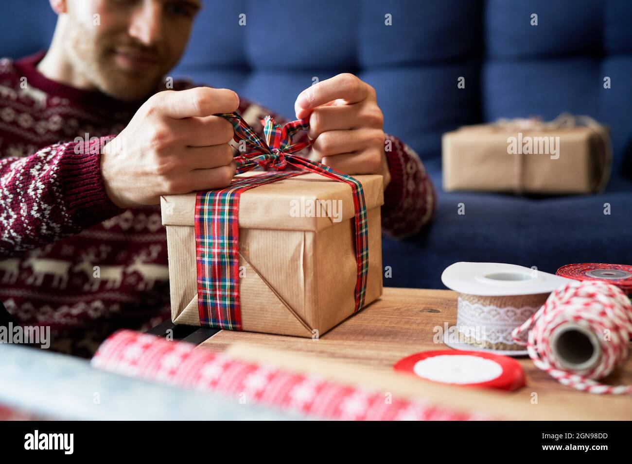 L'uomo che lega arco nastro sul regalo di Natale in casa Foto Stock