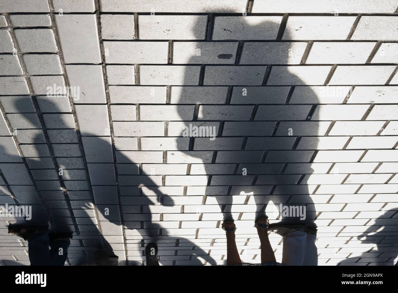 Ombre di una coppia e di altre persone sul pavimento di ciottoli all'aperto Foto Stock