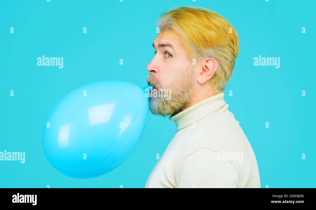 Preparazione alla festa. Uomo bearded che soffia il palloncino. Buon compleanno. Vacanza, celebrazione e stile di vita concetto. Foto Stock