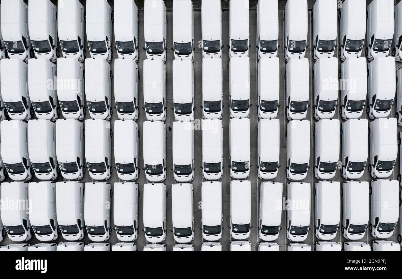 Vista aerea di file di nuovi furgoni bianchi presso la linea di produzione di un costruttore di motori con spazio di riproduzione Foto Stock
