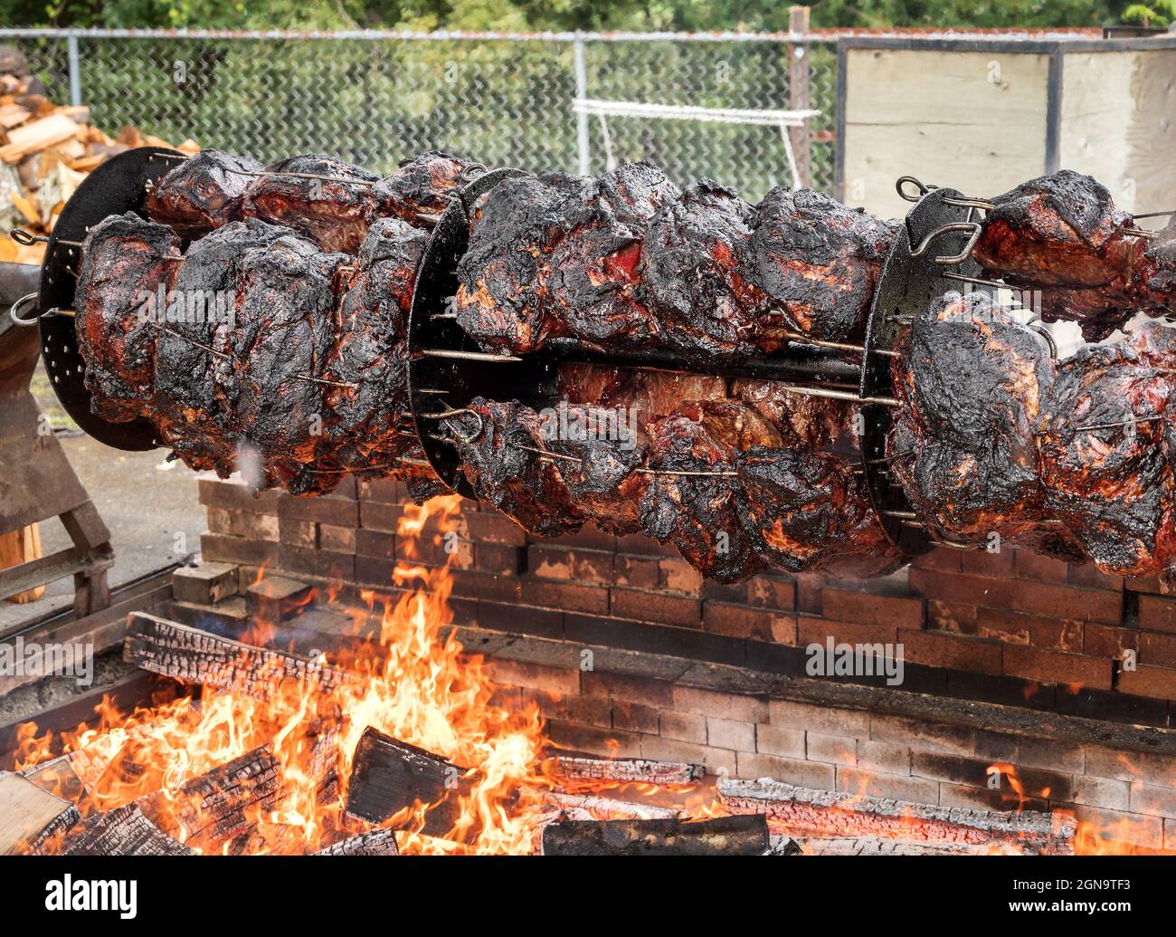 Ottocento libbre di manzo spiedato su un barbecue a motore su una buca di fuoco a fiamma aperta. Festival barbecue stand. Foto Stock