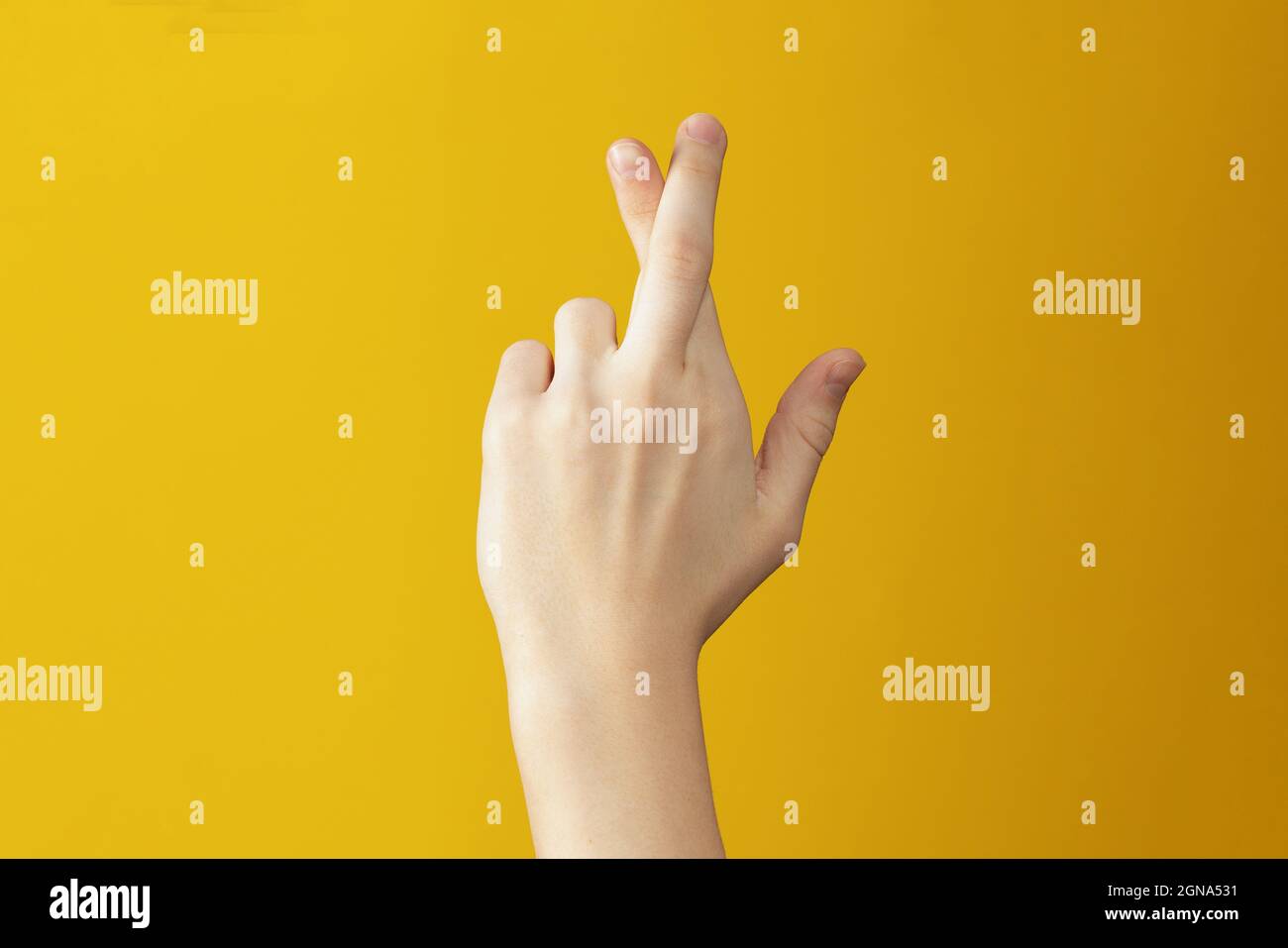 Mano su sfondo arancione che mostra le dita incrociate. Gesto che desidera buona fortuna Foto Stock