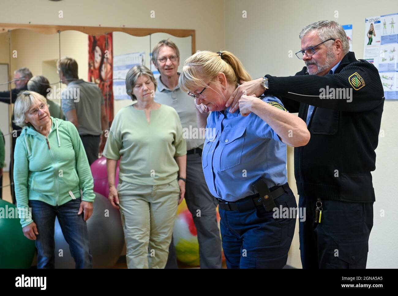 23 settembre 2021, Sassonia, Lipsia: I funzionari di polizia Stephan Weinhold (r) e Ramona Mertens (2° da destra) dimostrano ai partecipanti a un corso di assertività per gli anziani di Lipsia come liberarsi da una stanghetta. In otto unità, i partecipanti imparano ad agire con sicurezza nella vita quotidiana e a difendersi da delitti o crimini violenti. I corsi hanno avuto luogo dal 2008 - la polizia ha dovuto fare una pausa a causa della pandemia di Corona. Sono costituiti da parti teoriche e pratiche. In teoria, i partecipanti discutono con gli ufficiali come Foto Stock