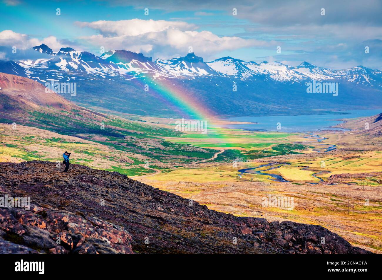 Il fotografo scatta foto con una leggera pioggia e un arcobaleno nelle montagne islandesi. Colorata mattinata estiva in Islanda, Europa. Stile artistico post Foto Stock
