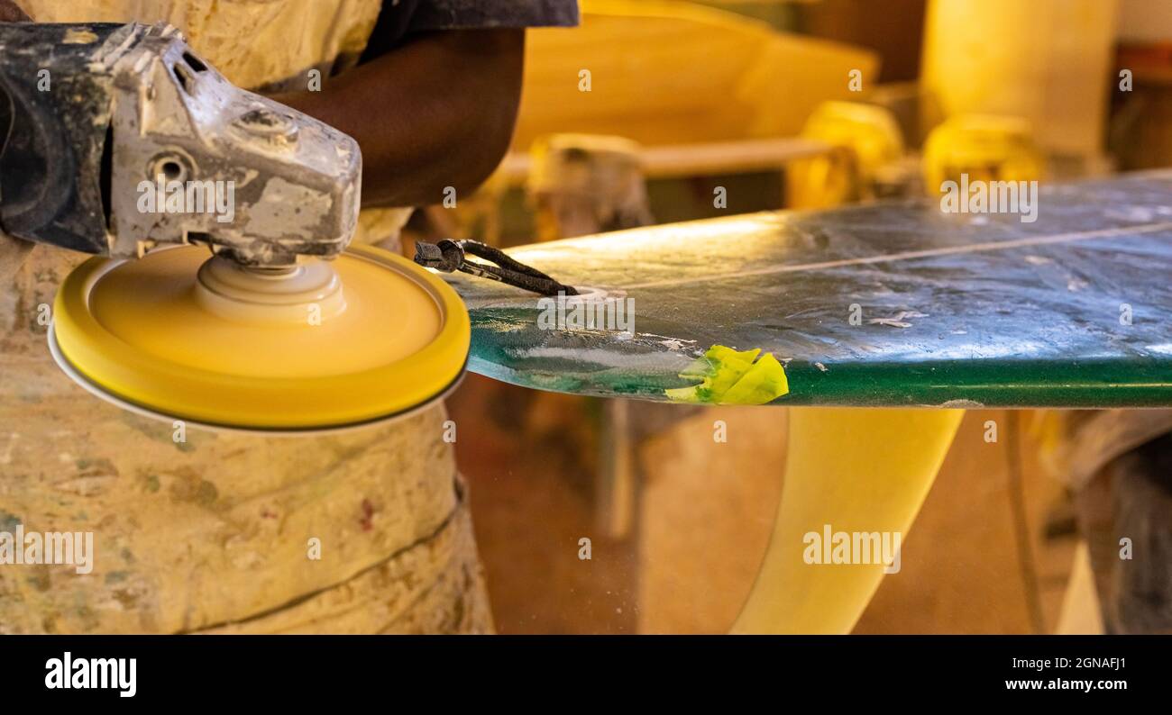 Primo piano di un artigiano africano tavola da surf Shaper lavorare in un'officina di riparazione Foto Stock