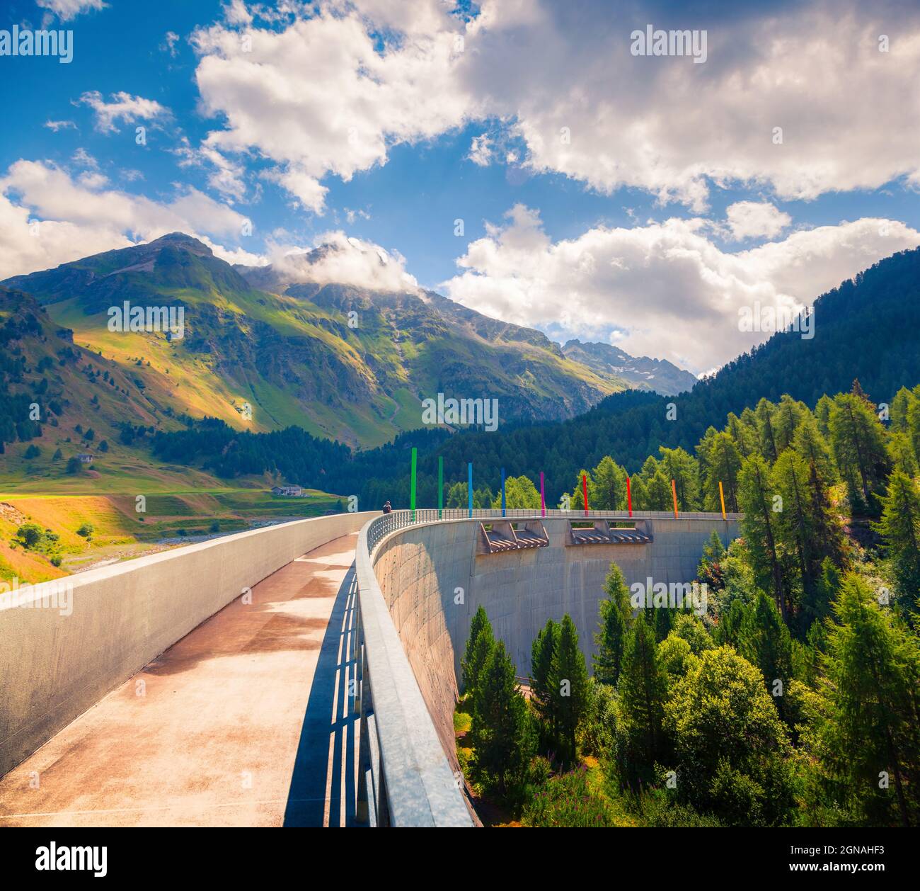 Walkinf sulla diga sul fiume Orlegna. Soleggiata vista estiva dalla cima del passo Maloja. Alpi svizzere, alta Engadina nel cantone dei Grigioni, Svizzera, Foto Stock