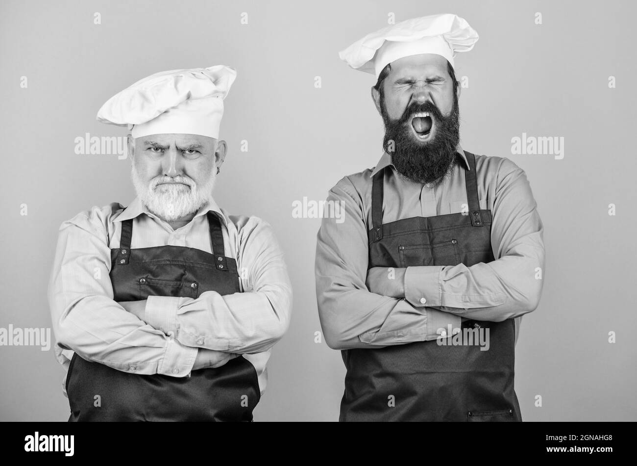 Ristorante per famiglie. Gli uomini dello chef indossano grembiuli. Padre e figlio hobby culinario. Cafe lavoratori. Cucina del ristorante. Industria culinaria. Personale del ristorante. Maturo Foto Stock