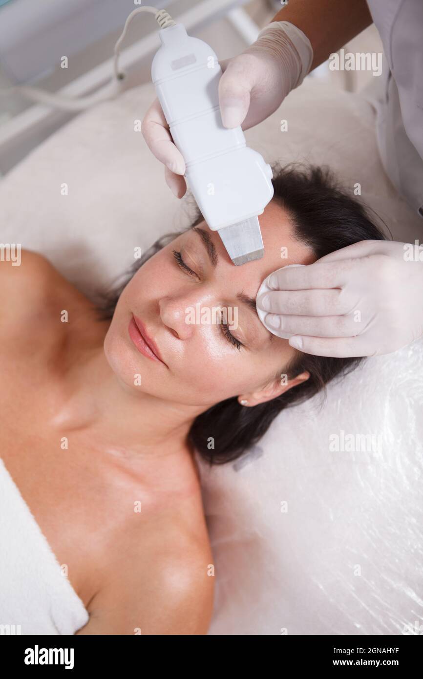 Primo piano verticale di un comstician che fa il viso ad ultrasuoni per un cliente Foto Stock