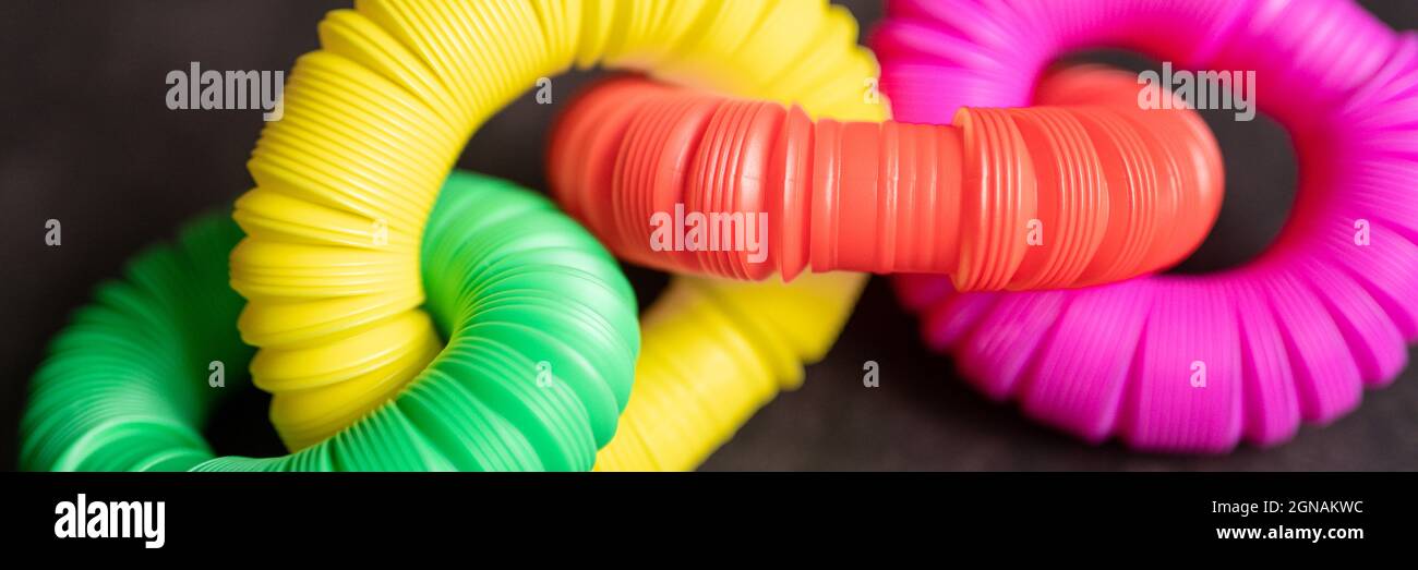 bambini anti stress sensoriale pop tubo in plastica fidget push giocattolo su un tavolo nero o sfondo pavimento. bambini piccoli pop tube giocattoli multicolore tonalità brillante col Foto Stock
