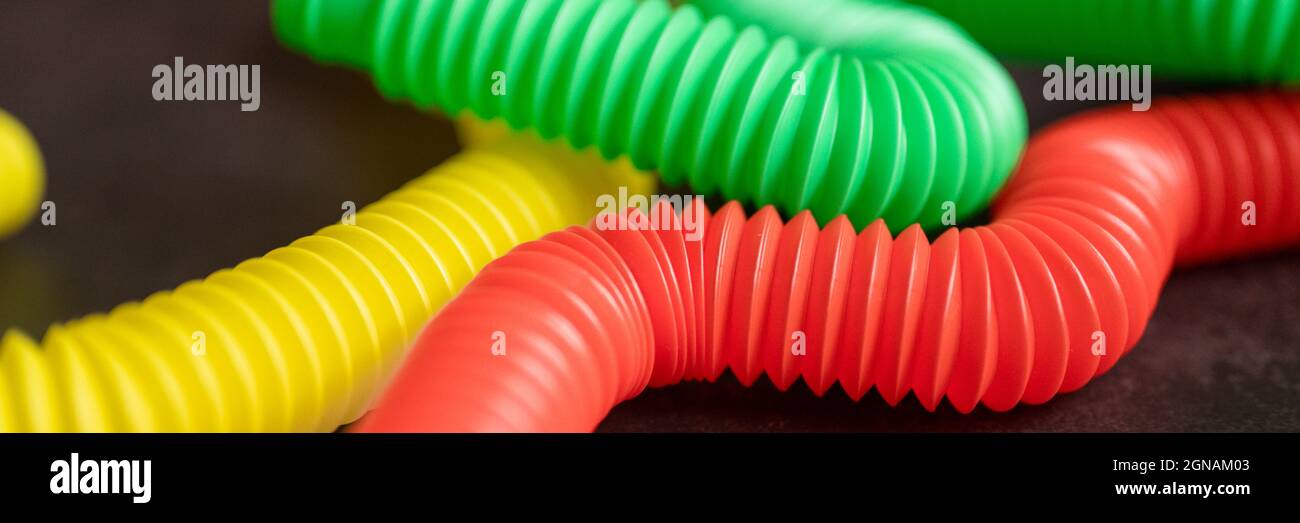 bambini anti stress sensoriale pop tubo in plastica fidget push giocattolo su un tavolo nero o sfondo pavimento. bambini piccoli pop tube giocattoli multicolore tonalità brillante col Foto Stock