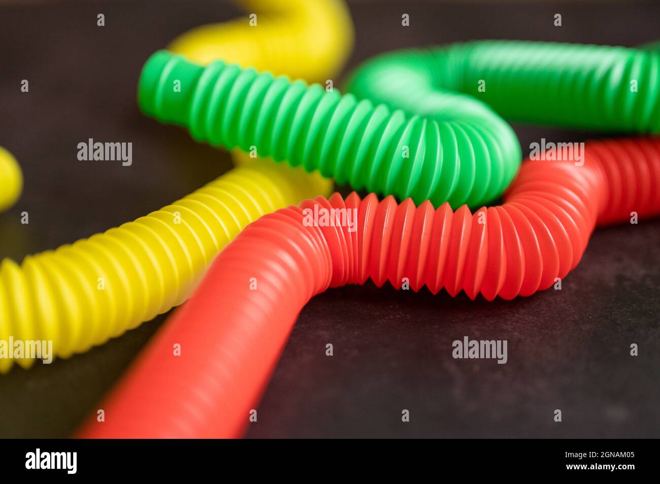 bambini anti stress sensoriale pop tubo in plastica fidget push giocattolo su un tavolo nero o sfondo pavimento. bambini piccoli pop tube giocattoli multicolore tonalità brillante col Foto Stock