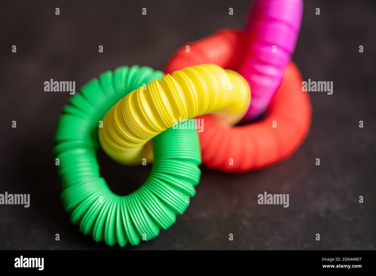 bambini anti stress sensoriale pop tubo in plastica fidget push giocattolo su un tavolo nero o sfondo pavimento. bambini piccoli pop tube giocattoli multicolore tonalità brillante col Foto Stock