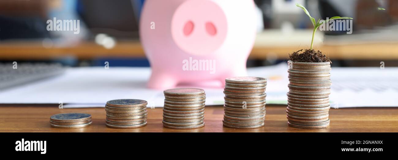 Pile di monete e di porcellini sono sul tavolo Foto Stock