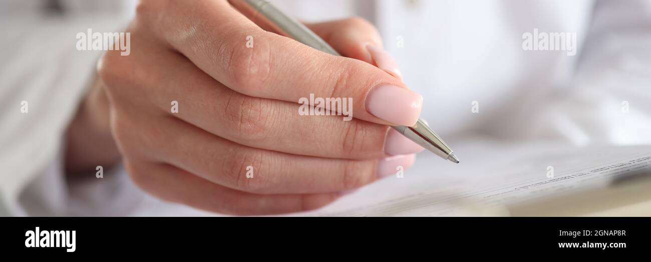 Il medico della donna scrive i dati del paziente in documenti con la penna Foto Stock