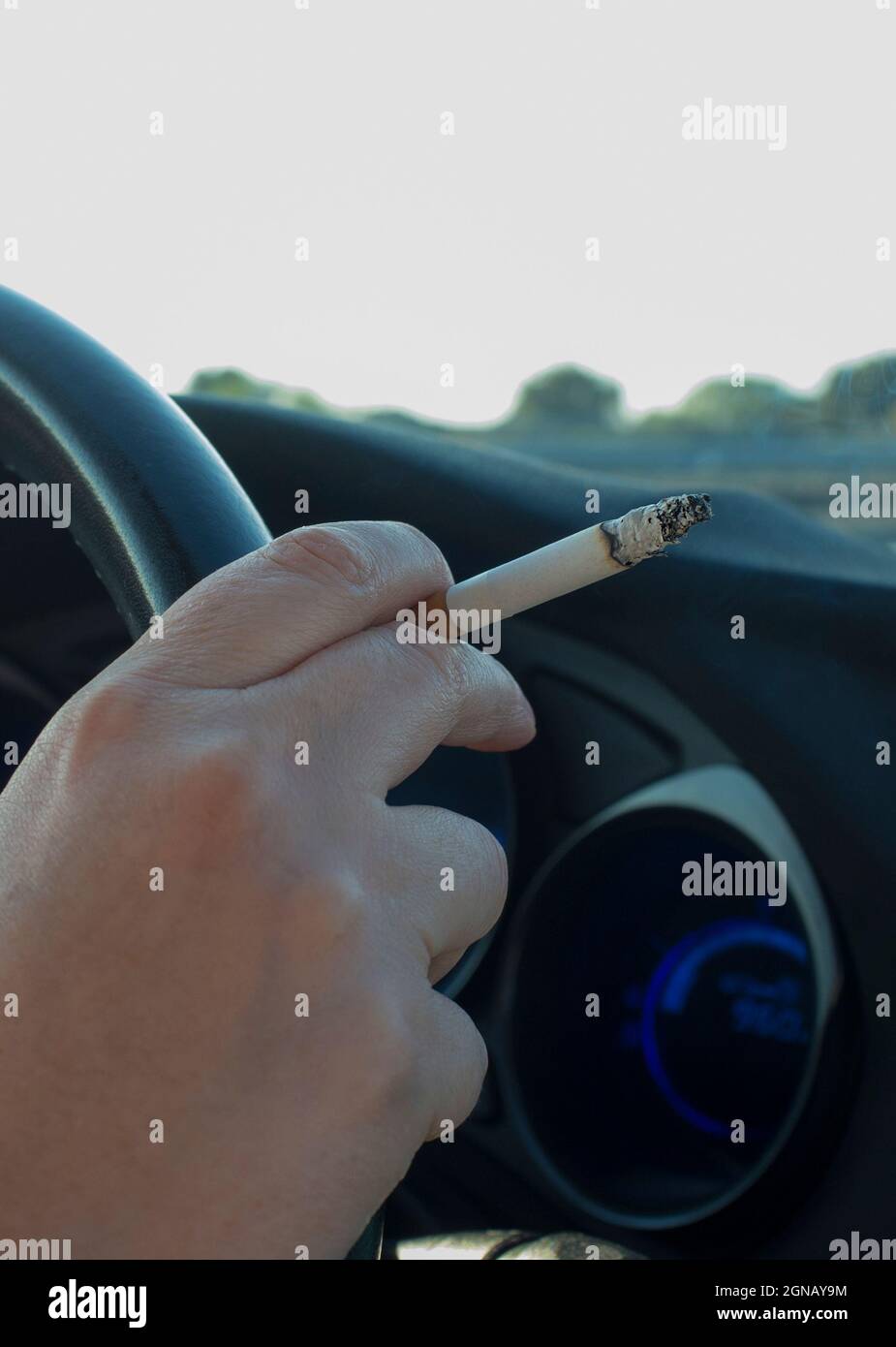 Donna che fuma durante la guida. Concetto di causa di incidenti stradali distratti. Vista interna dell'auto Foto Stock