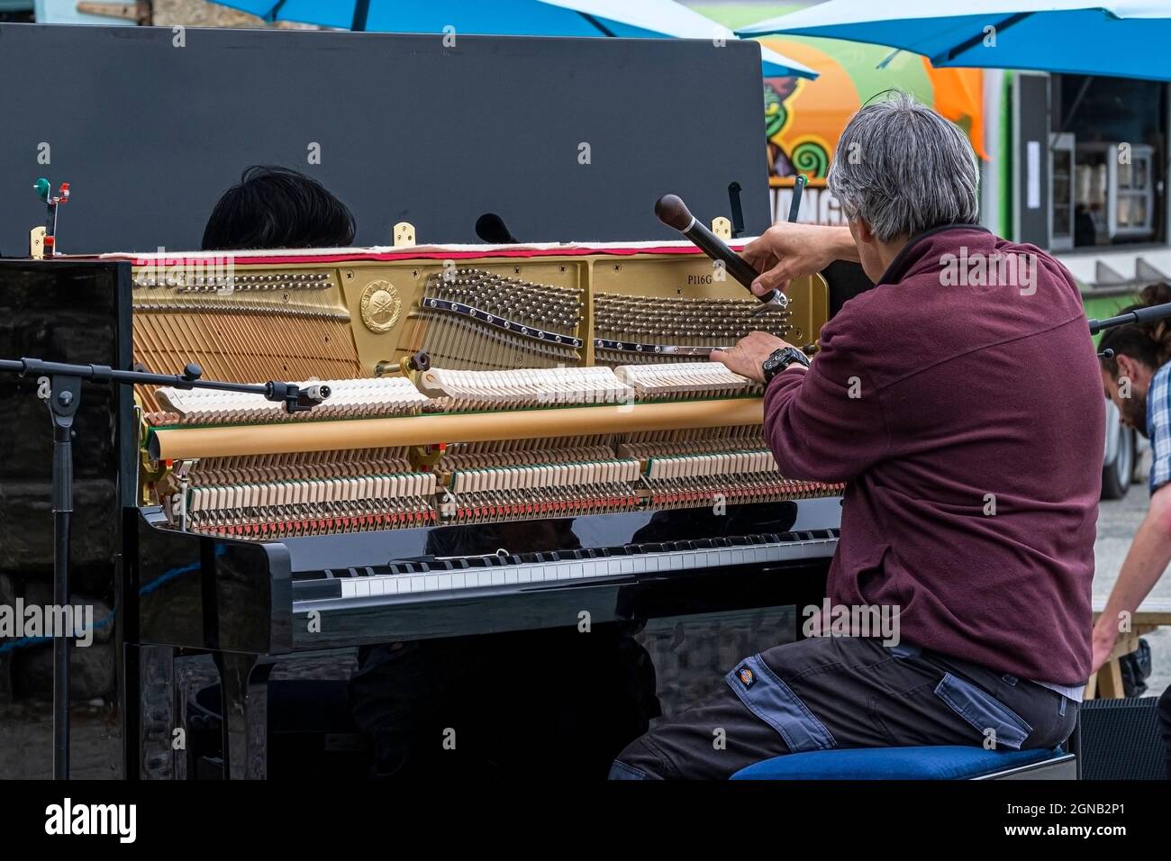 Un sintonizzatore per pianoforte che sintonizza un pianoforte verticale in preparazione di un recital per pianoforte all'aperto. Foto Stock