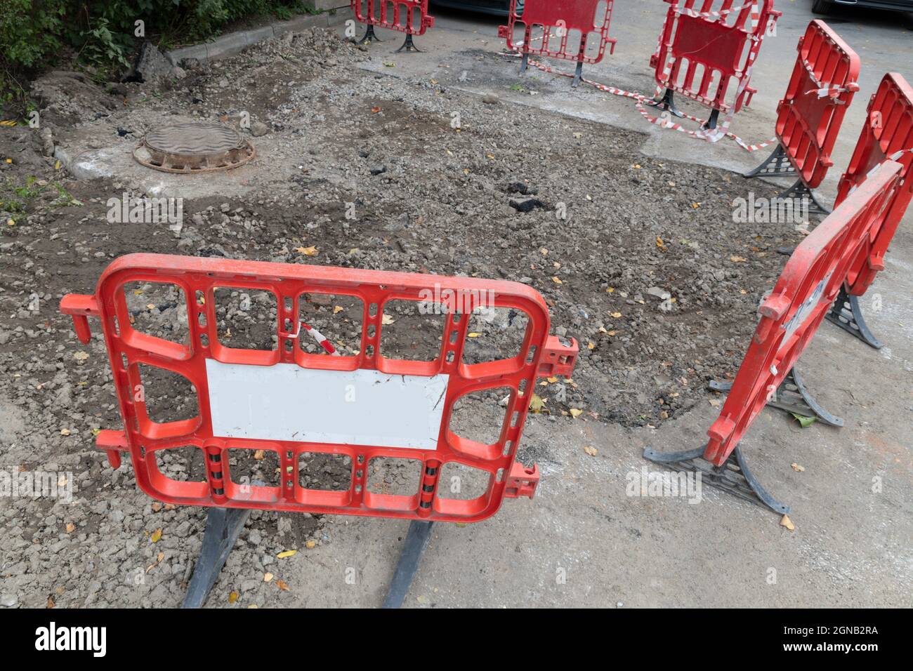 Trama di terreno appena scavato dopo un incidente nel sistema di riscaldamento della città protetto da una recinzione rossa Foto Stock