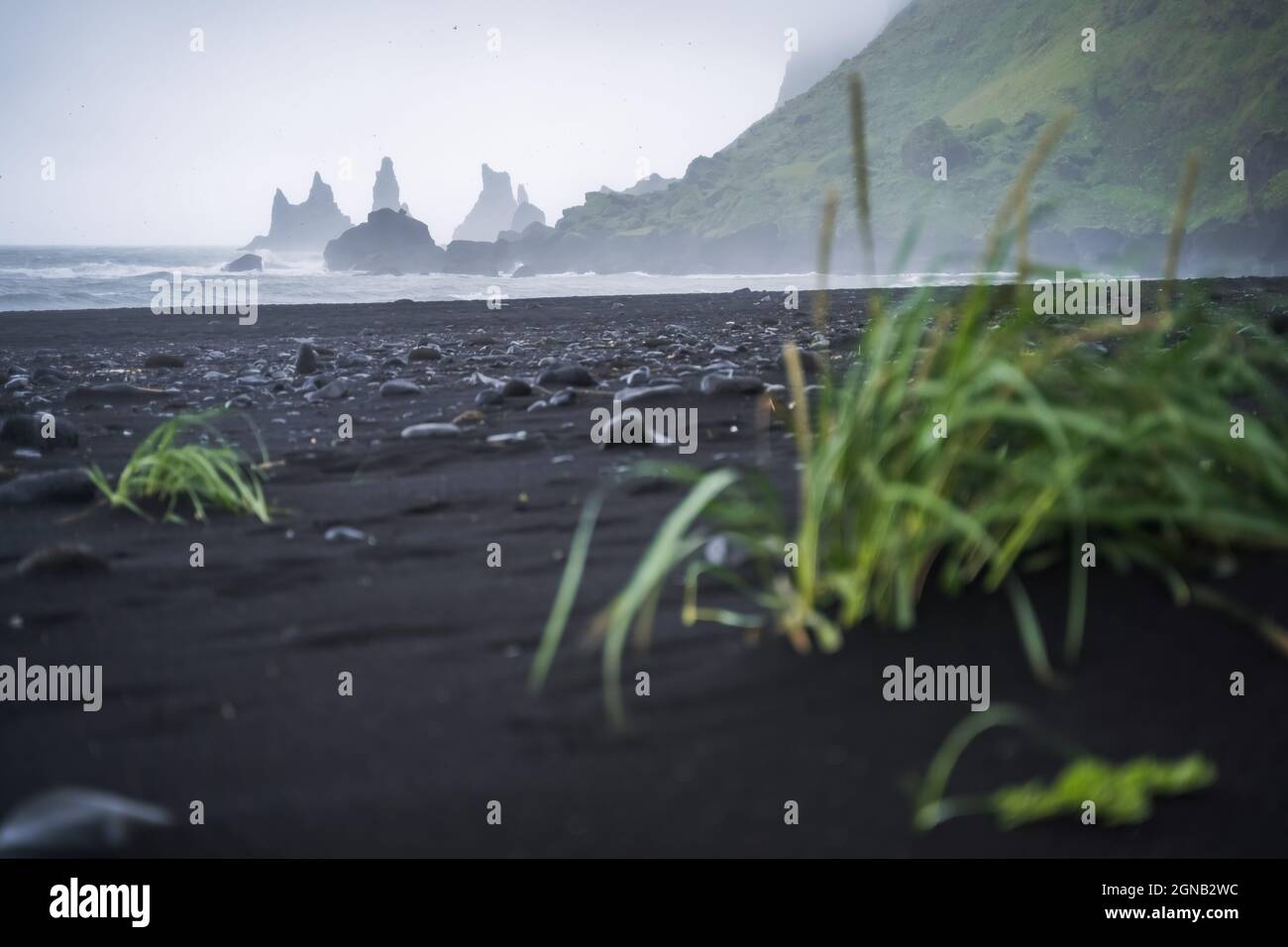 Spiaggia nera a Vik con le famose formazioni rocciose di Reynisdrangar e il monte Reynisfjall in un oceano tempestoso. Islanda meridionale Foto Stock