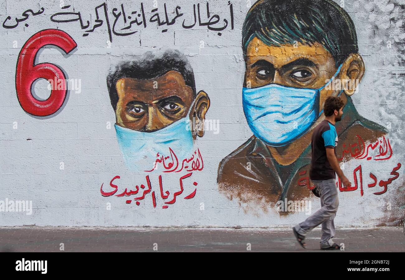 Città di Gaza, striscia di Gaza, Palestina. 23 settembre 2021. Gaza, Palestina. 23 settembre 2021. I palestinesi camminano vicino a un murale raffigurante i 6 prigionieri palestinesi fuggiti dalla prigione di Gilboa il 6 settembre 2021. Anche se Israele ha catturato tutti e sei i prigionieri palestinesi fuggiti dalla prigione di massima sicurezza israeliana, i palestinesi hanno salutato i fuggitivi come eroi nella loro lotta contro l'occupazione israeliana (immagine di credito: © Ahmad Hasaballah/IMAGESLIVE via ZUMA Press Wire) Foto Stock