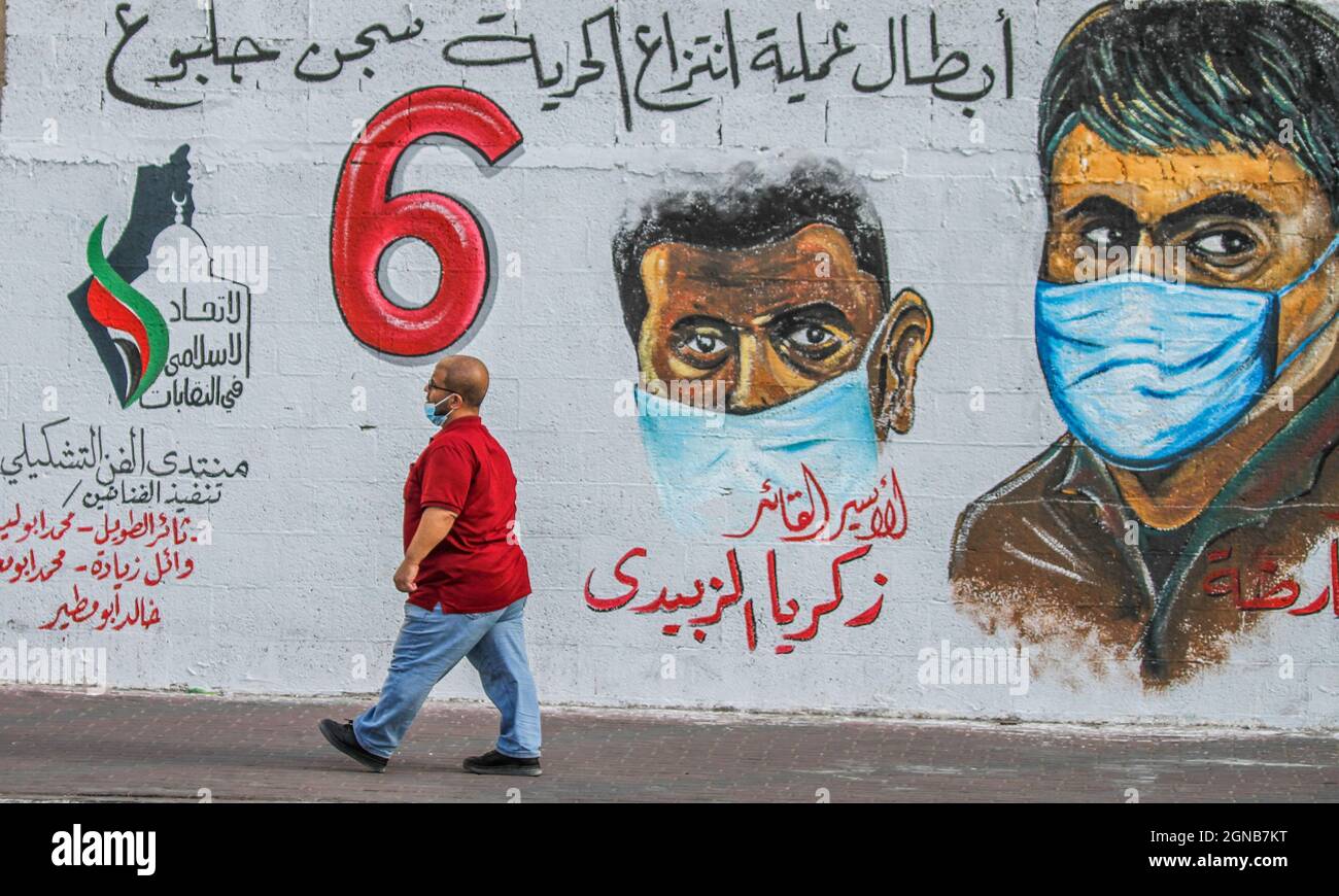 Città di Gaza, striscia di Gaza, Palestina. 23 settembre 2021. Gaza, Palestina. 23 settembre 2021. I palestinesi camminano vicino a un murale raffigurante i 6 prigionieri palestinesi fuggiti dalla prigione di Gilboa il 6 settembre 2021. Anche se Israele ha catturato tutti e sei i prigionieri palestinesi fuggiti dalla prigione di massima sicurezza israeliana, i palestinesi hanno salutato i fuggitivi come eroi nella loro lotta contro l'occupazione israeliana (immagine di credito: © Ahmad Hasaballah/IMAGESLIVE via ZUMA Press Wire) Foto Stock