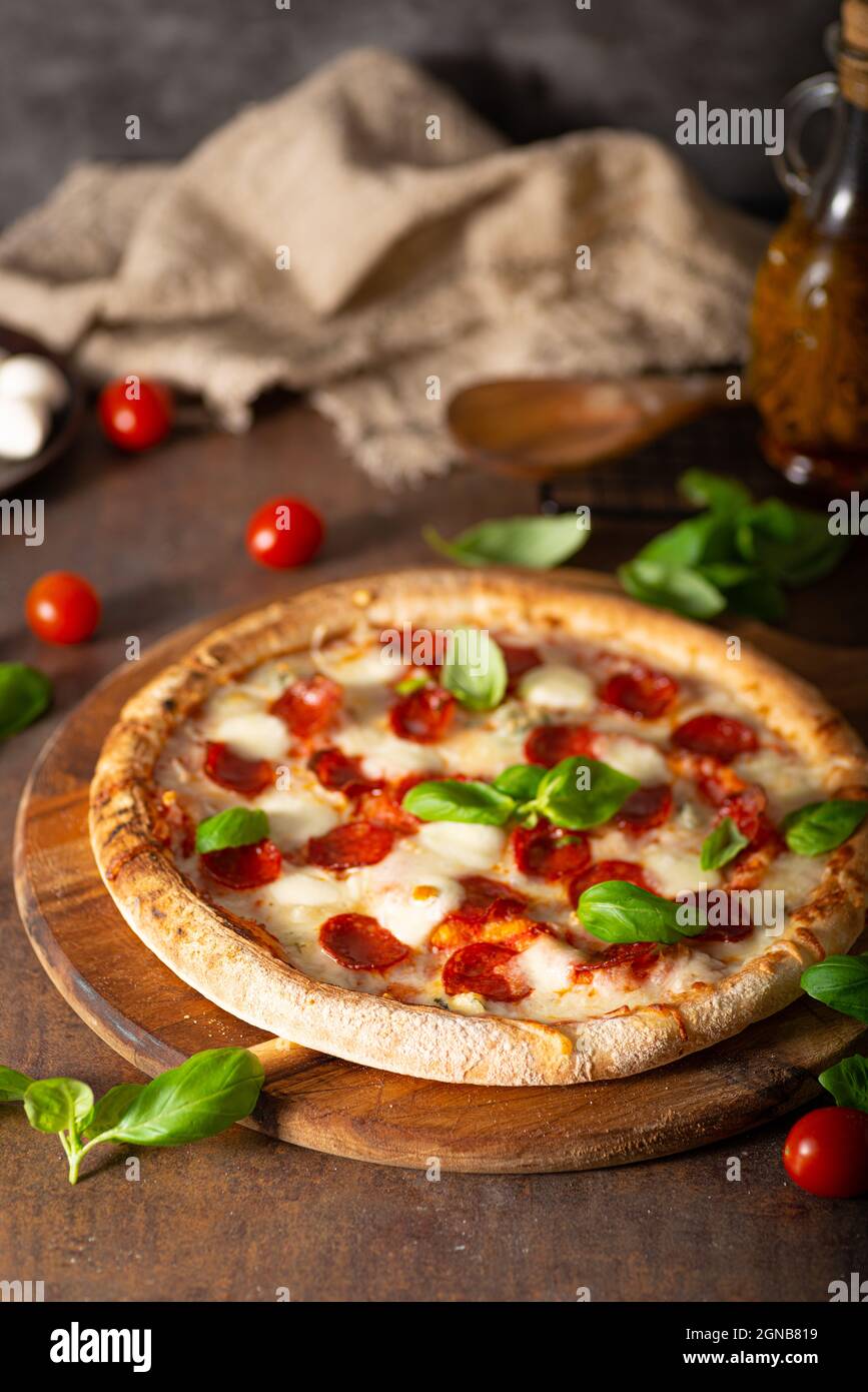 Pizza prelibata con salumi caldi, parmigiano e basilico fresco Foto Stock