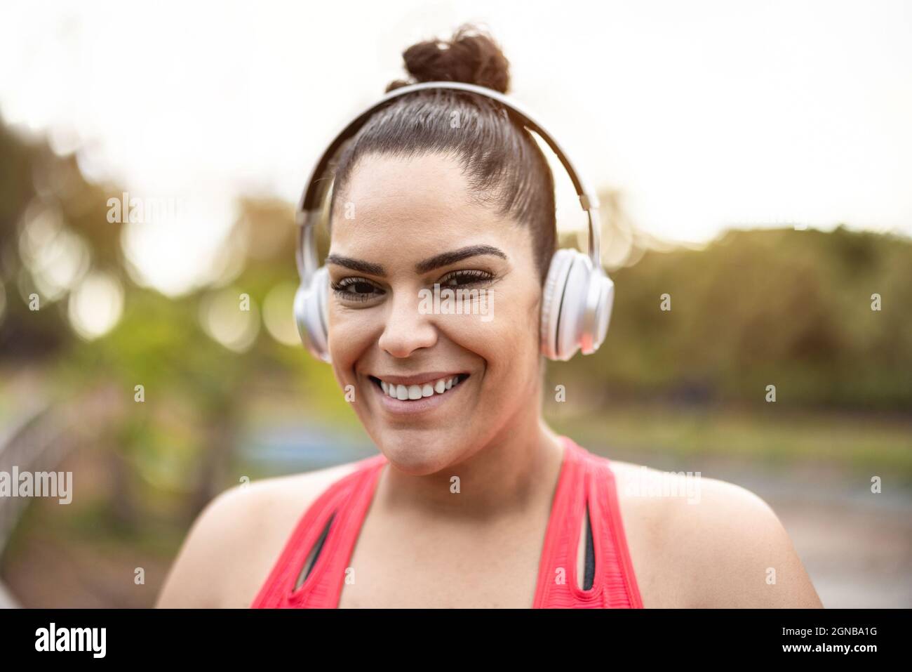 Ritratto di donna curvy che ascolta la musica della playlist dopo la routine di jogging Outdoor - Focus sul viso Foto Stock