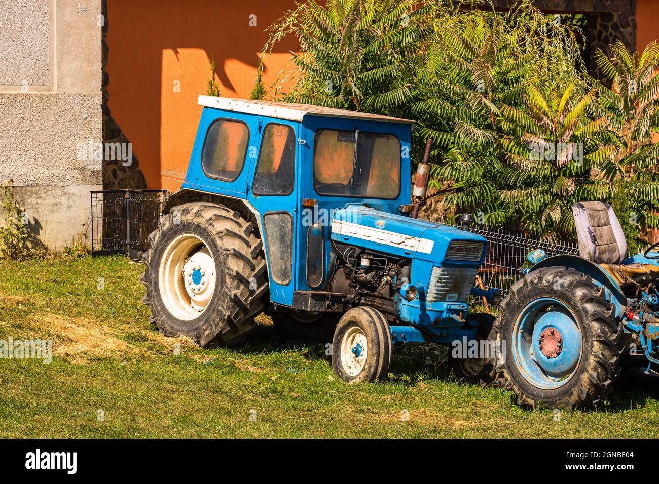Vecchio trattore d'epoca blu di fronte al terreno agricolo nel villaggio di Viscri, Romania Foto Stock