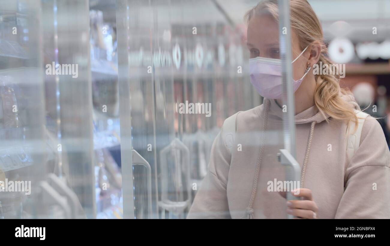 Donna in maschera di acquisto yogurt in supermercato Foto Stock