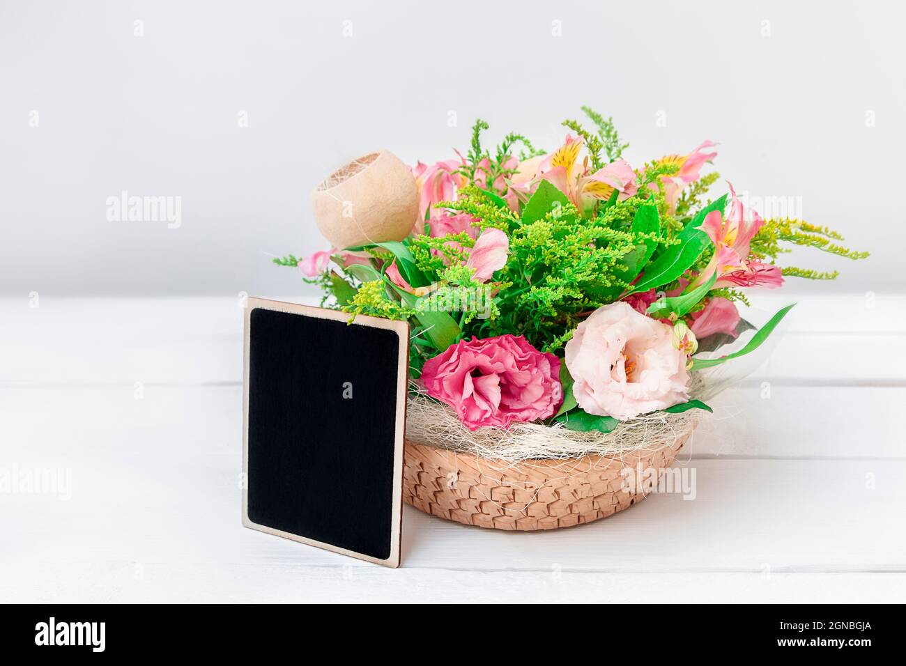 Mockup con bouquet di fiori e bordo nero vuoto su sfondo bianco tavolo con spazio copia Foto Stock