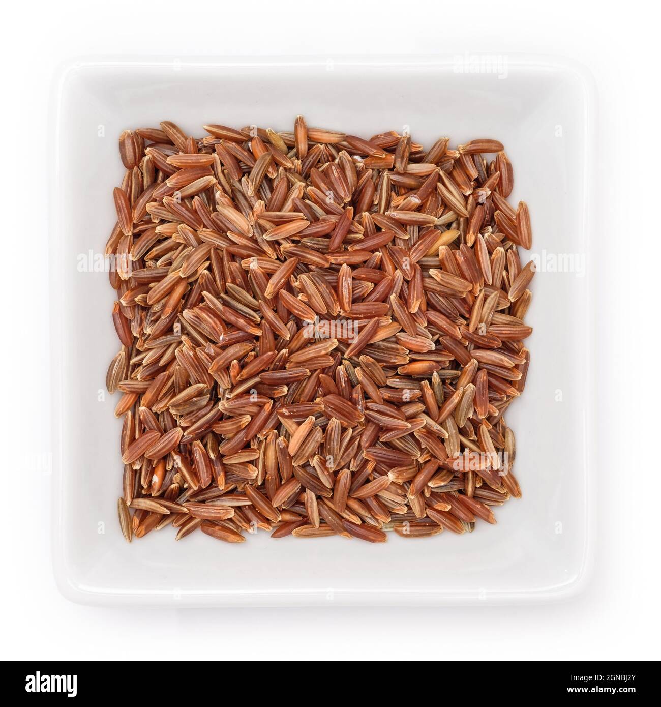 Vista dall'alto del riso camargue crudo marrone-rosso in una ciotola su sfondo bianco Foto Stock