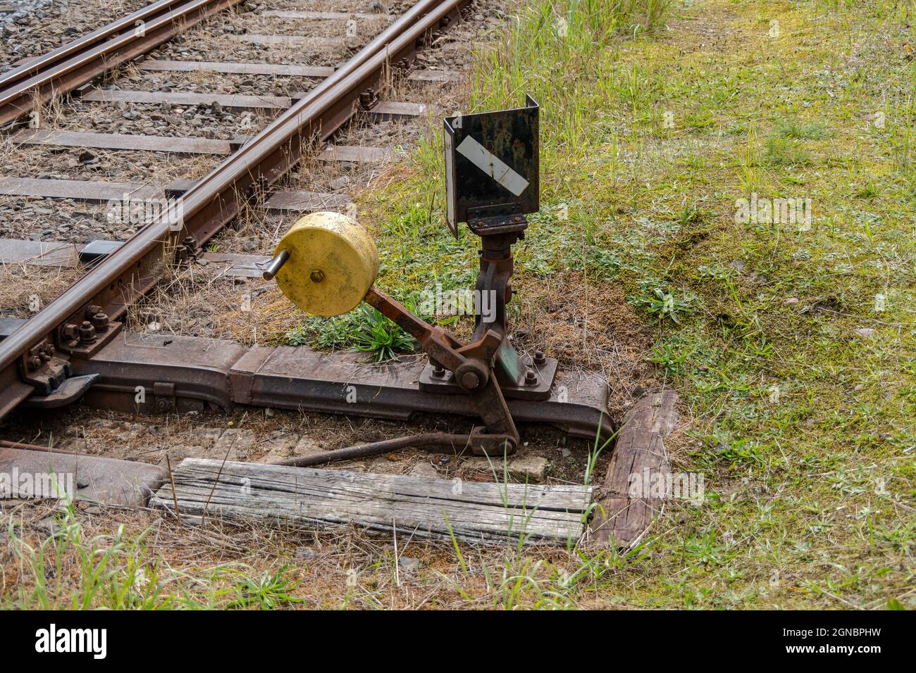 Interruttore manuale con leva, peso e segnale e vecchi binari del treno Foto Stock