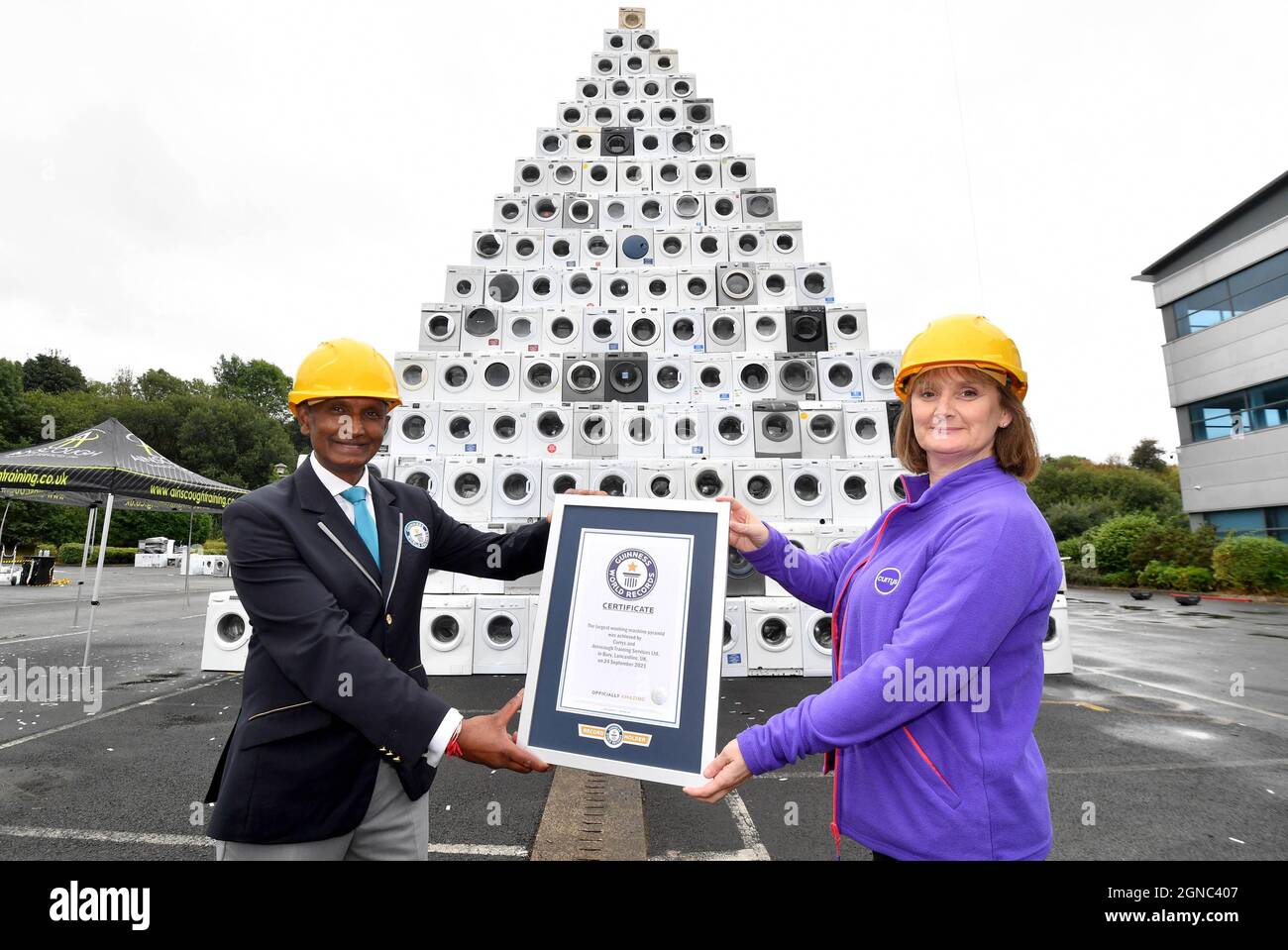 USO EDITORIALE SOLO Pravin Patel, Guinness World Records giudice ufficiale con Lindsey Hazlehurst da Currys PC World, a Bolton, come il rivenditore è presentato con il suo titolo Guinness World Records per la 'più grande piramide di lavatrici', per segnare National Recycling Week. Data foto: Venerdì 24 settembre 2021. Foto Stock