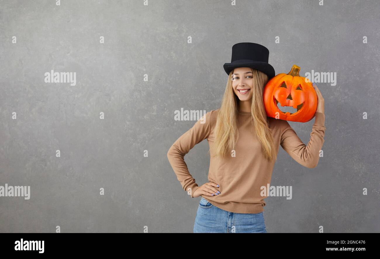 Ritratto di donna felice nel cappello di testa che tiene la zucca di Halloween sullo sfondo spazio copia Foto Stock