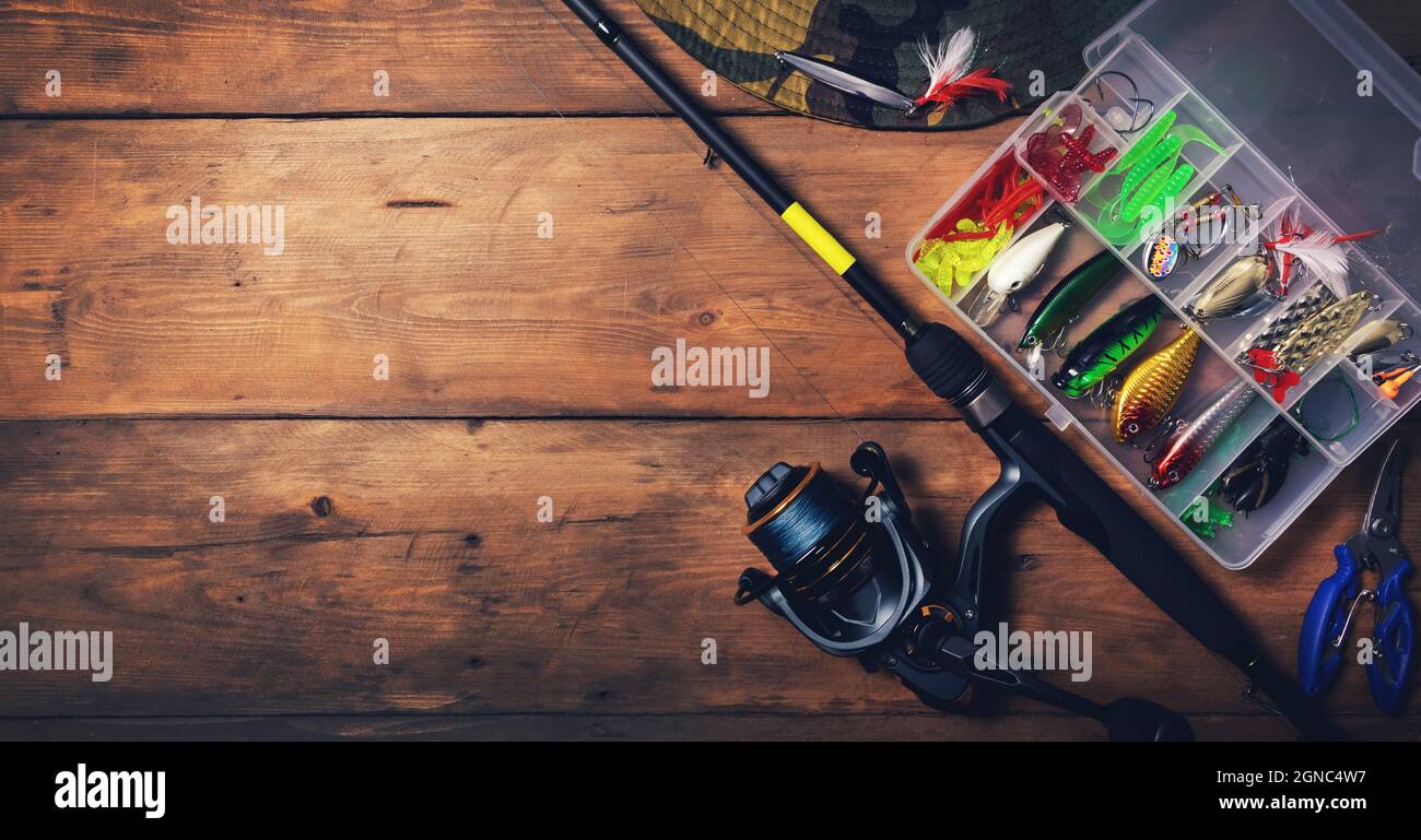 attrezzatura da pesca - canna da filatura con scatola di esche e attrezzature su sfondo di legno. spazio copia Foto Stock