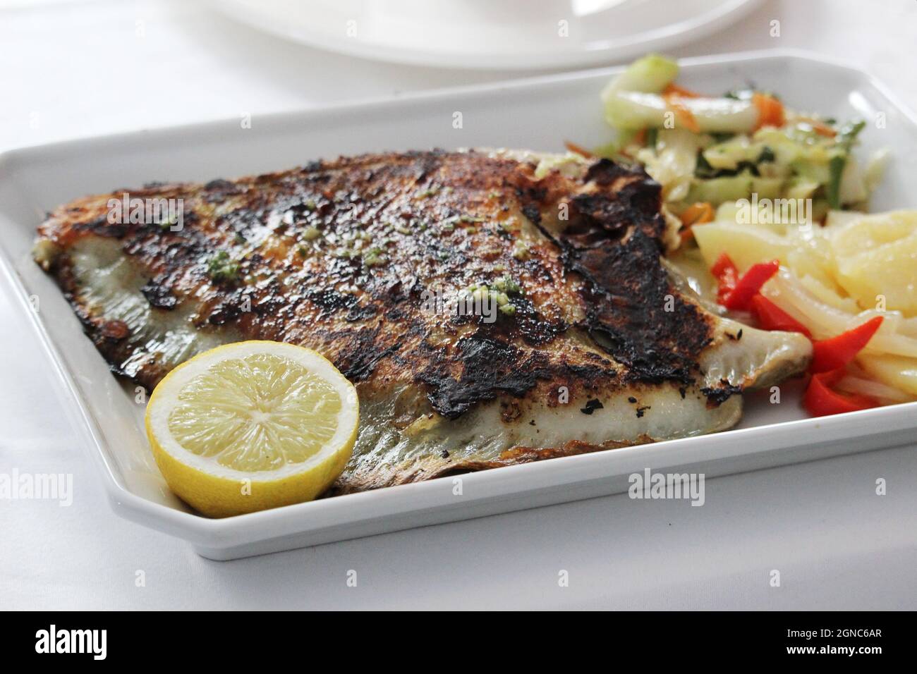 Porzione di delizioso rombo alla griglia con limone e verdure Foto Stock