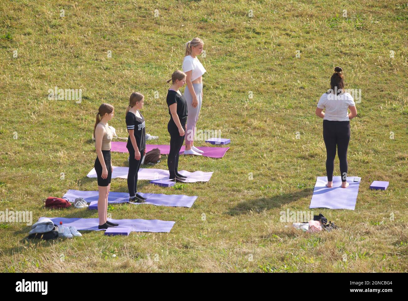 Lezione di yoga tenuto sull'erba in un giardino pubblico, Brighton & Hove, East Sussex, Engerd, Regno Unito. Foto Stock