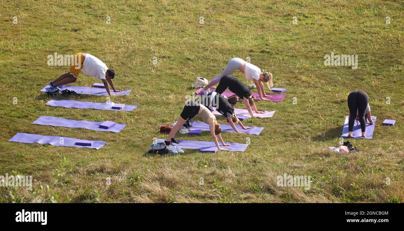 Lezione di yoga tenuto sull'erba in un giardino pubblico, Brighton & Hove, East Sussex, Engerd, Regno Unito. Foto Stock