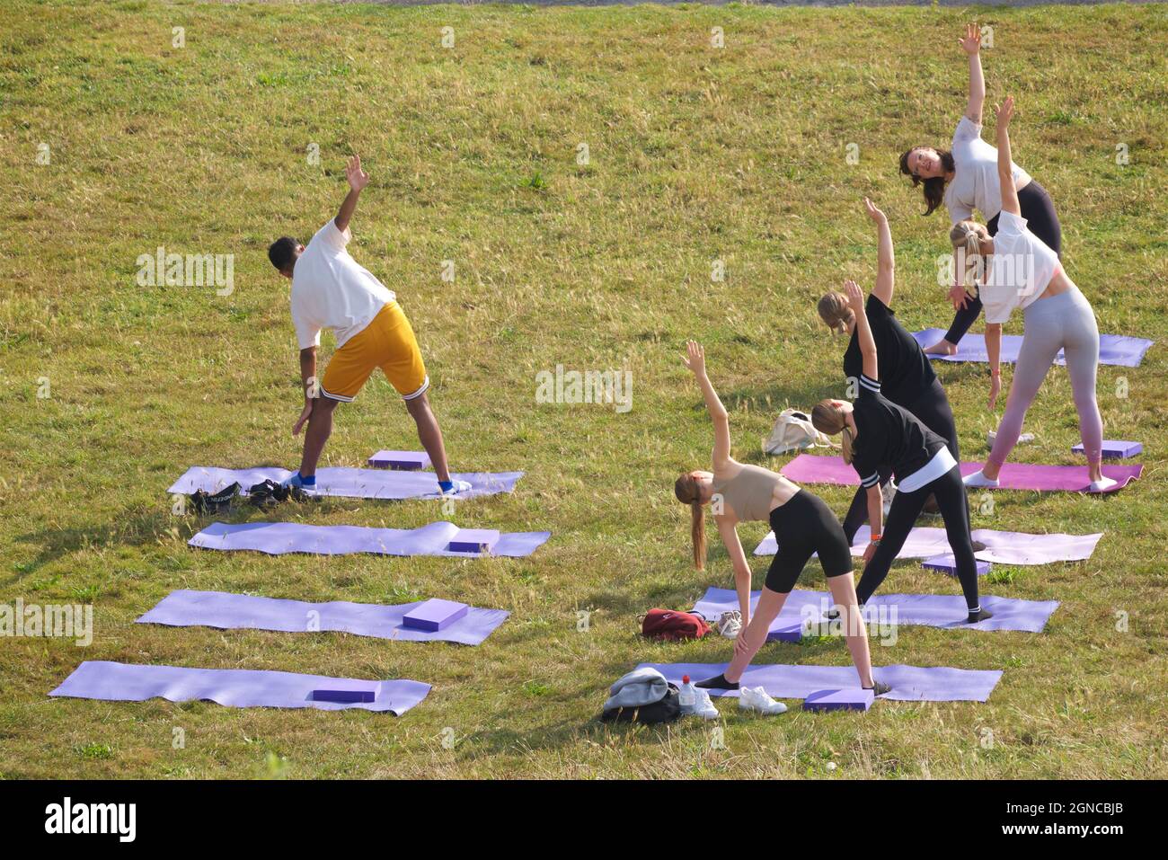 Lezione di yoga tenuto sull'erba in un giardino pubblico, Brighton & Hove, East Sussex, Engerd, Regno Unito. Foto Stock