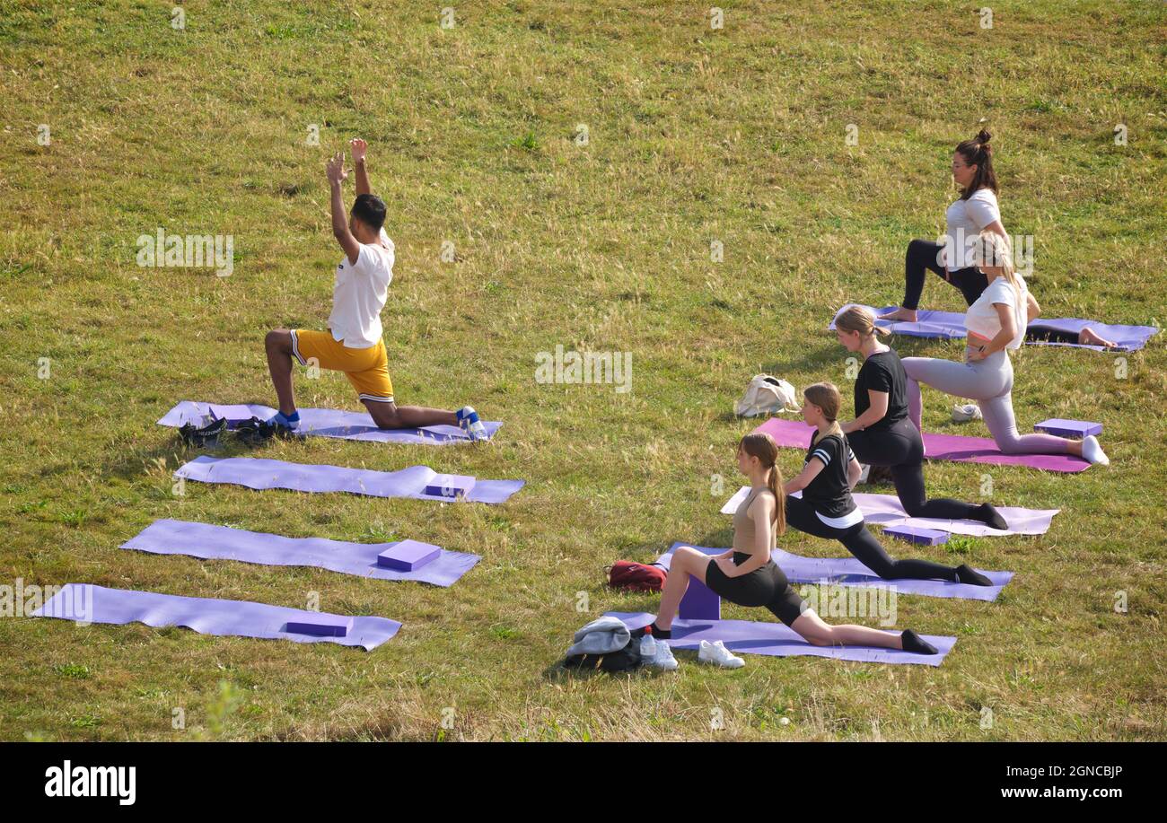 Lezione di yoga tenuto sull'erba in un giardino pubblico, Brighton & Hove, East Sussex, Engerd, Regno Unito. Foto Stock