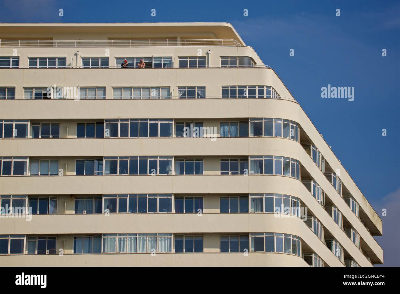 Edificio Art Deco della Corte delle Ambasciate, Brighton. East Sussex, Inghilterra, Regno Unito. Coppia che guarda fuori dal balcone al piano superiore Foto Stock
