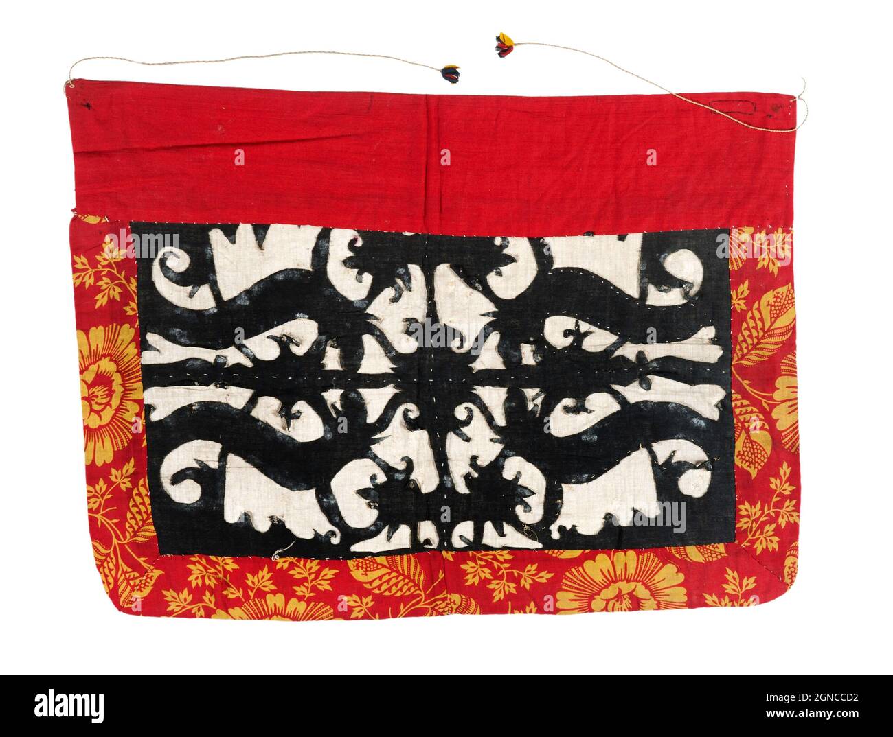 Una gonna in cotone tessuto. Il bordo superiore è rosso, il bordo inferiore e i bordi laterali sono rossi con fiori gialli. Il centro è bianco, con quattro figure di cani stilizzati con cuciture nere. I lacci sono realizzati in filato giallo e terminano in ciuffi multicolore. La gonna è usata per vestire il defunto. Foto Stock