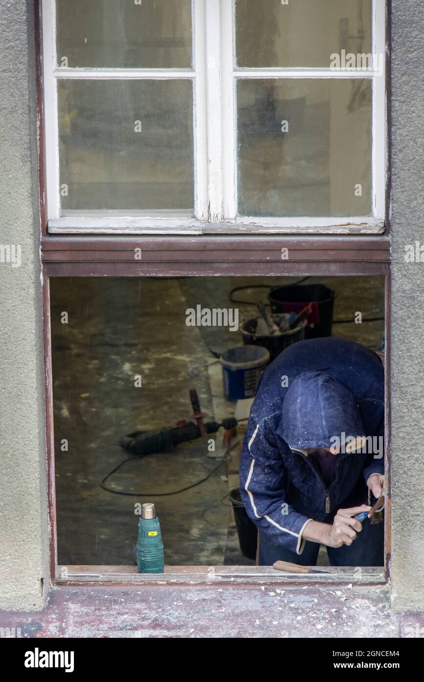 Un operaio lavora alla ricostruzione di una finestra nella casa Foto Stock