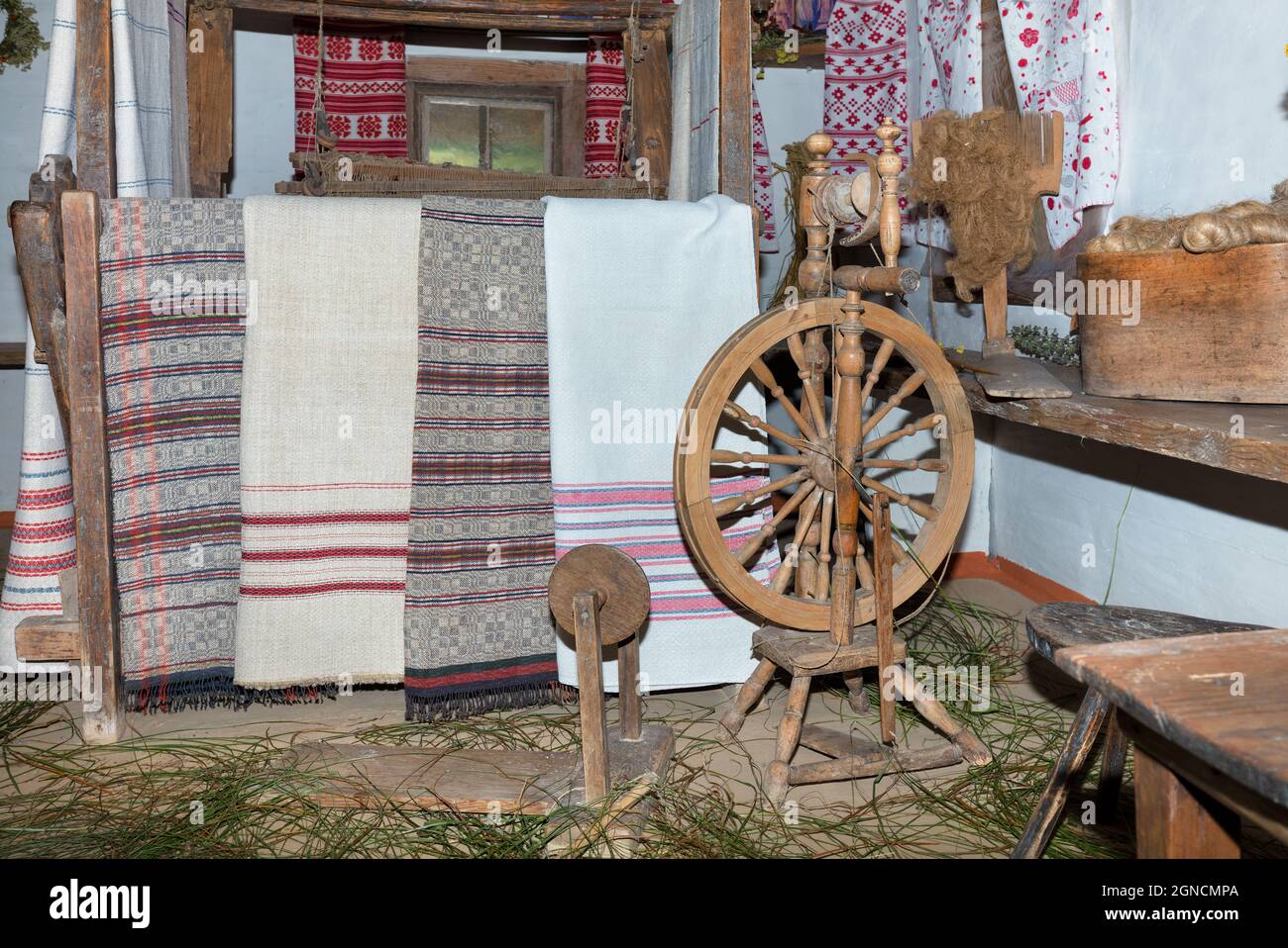 Un vecchio filatoio ucraino di legno sullo sfondo della decorazione interna di una vecchia capanna rurale in un tradizionale stile ucraino. Foto Stock