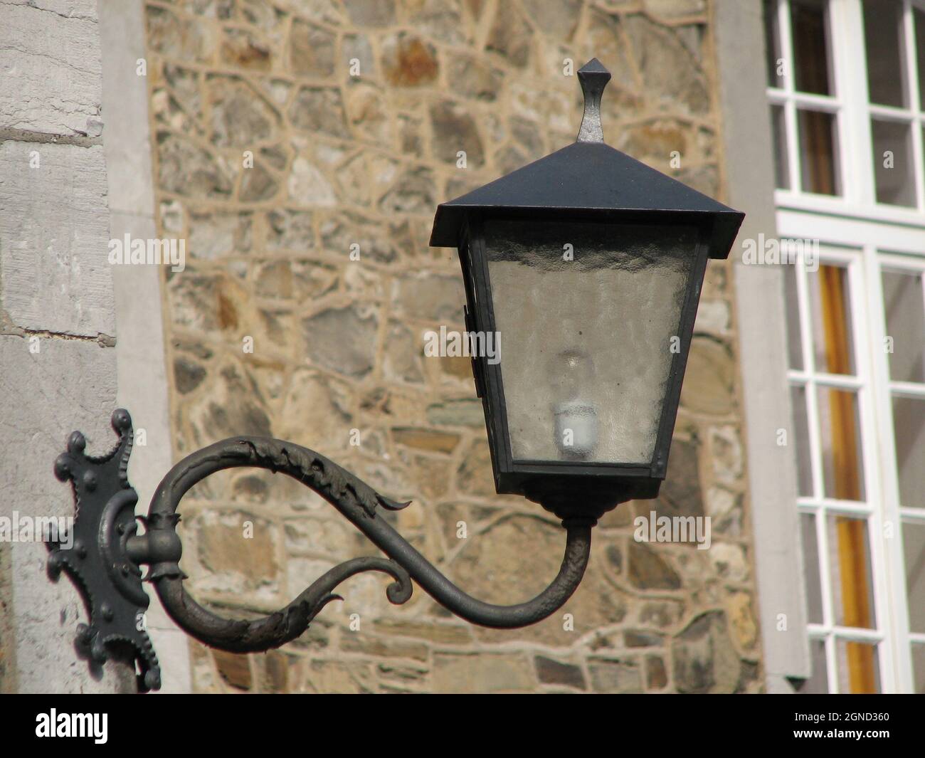 Vista di una lanterna appesa al palo sul muro della strada Foto Stock