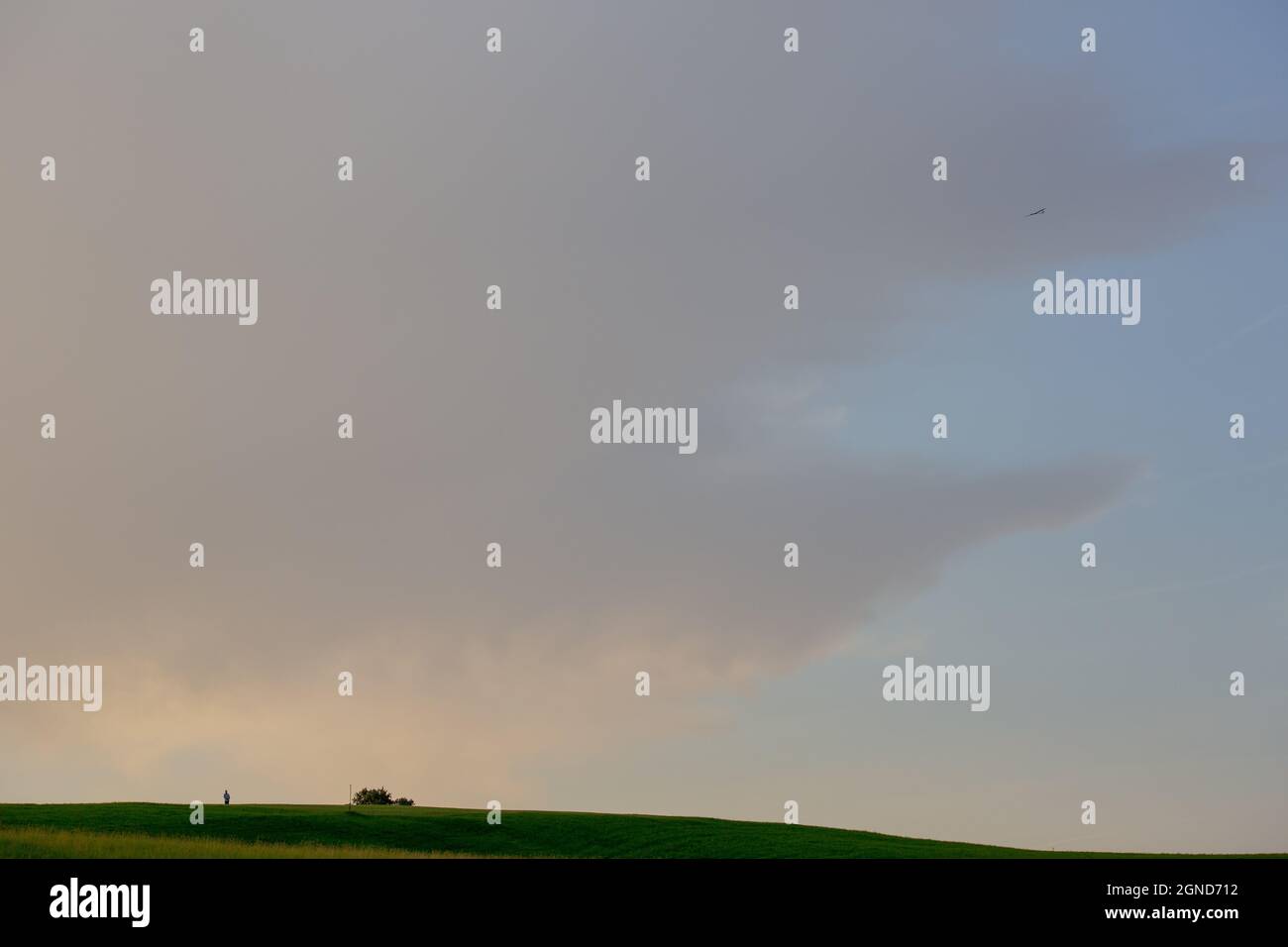 Si tratta di un'immagine panoramica ultra larga di un modello volantino con un telecomando nelle sue mani. Il modello in scala è piuttosto lontano in alto nel cielo. Foto Stock