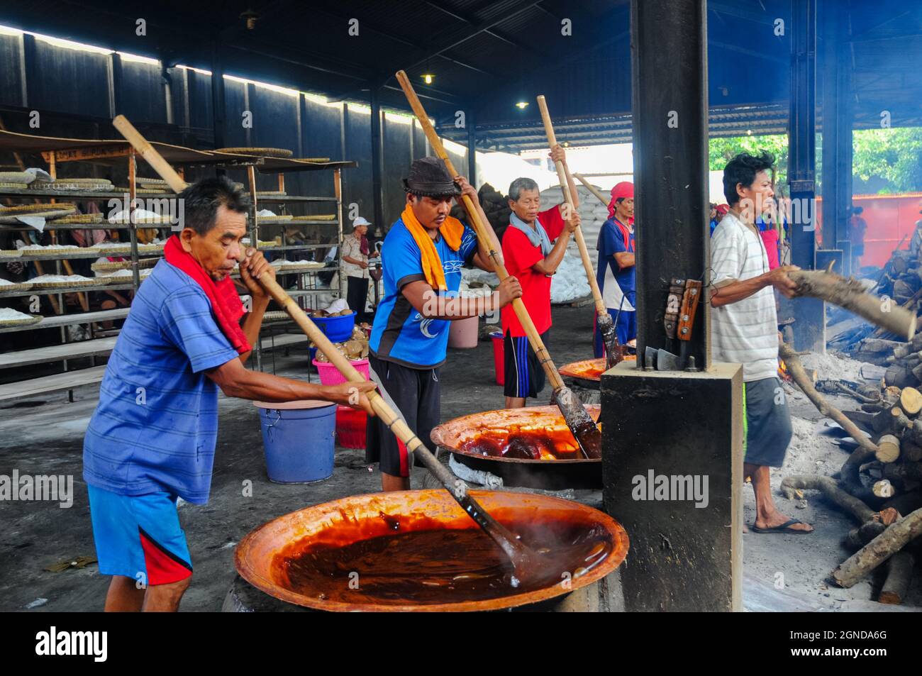 I lavoratori della fabbrica tradizionale di torte, vale a dire Keranjang e Dodol torte, stanno impastando l'impasto che viene cucinato su una stufa a legna. Foto Stock