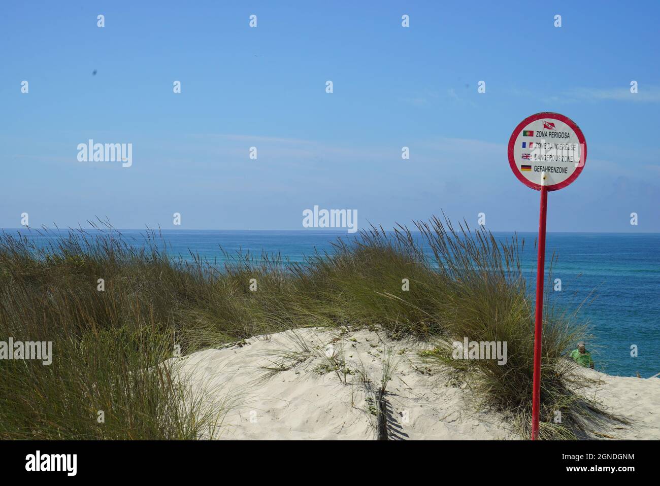 Primo piano di un cartello zona pericolosa in quattro lingue su una spiaggia Foto Stock