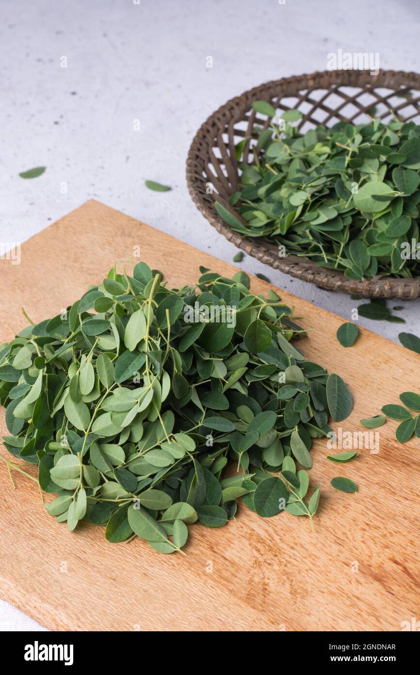 moringa o drumstick lascia su un tagliere di legno, pronto a cucinare Foto Stock