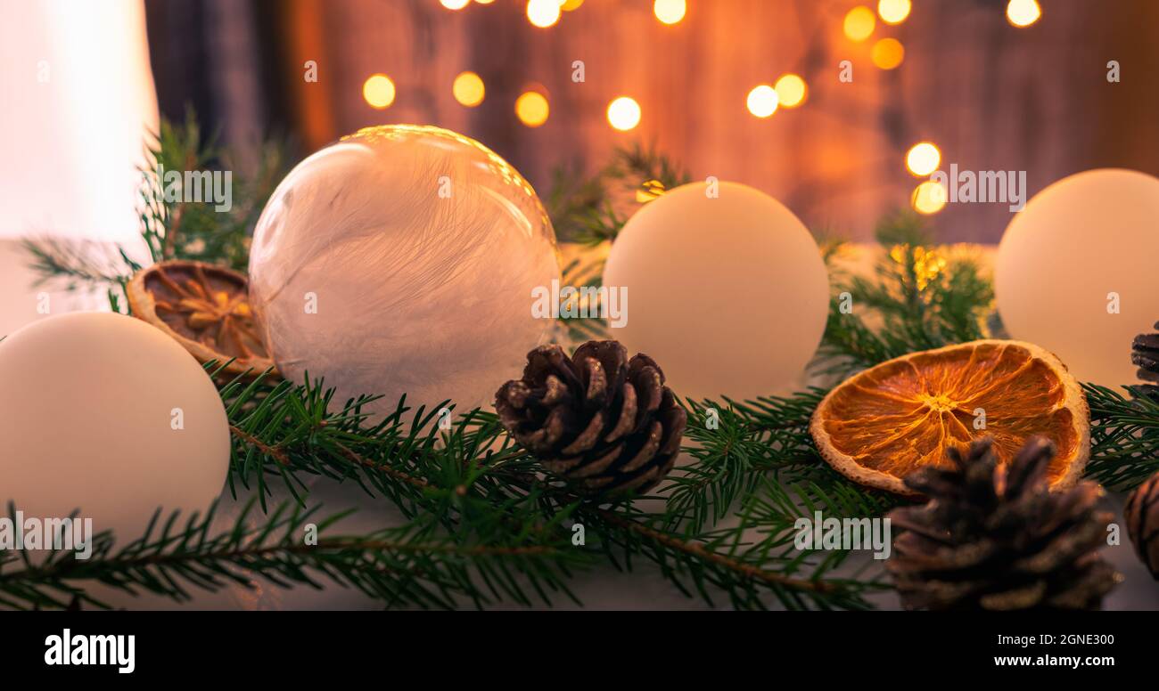 Set di decorazioni natalizie composto da palle bianche di Natale, rametti di abete rosso, coni e arance e limoni secchi. Luci schiarite sullo sfondo. Foto Stock